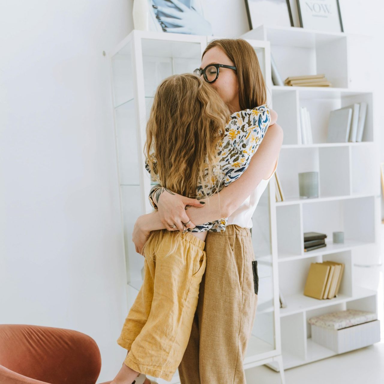 A joyful moment between mother and daughter hugging in a bright, modern home interior.