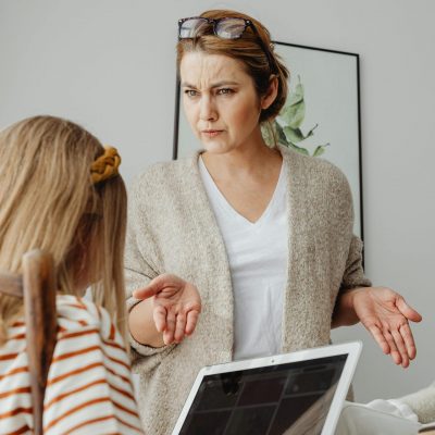 A mother scolds her daughter over tablet usage in a home setting. Tension is visible.